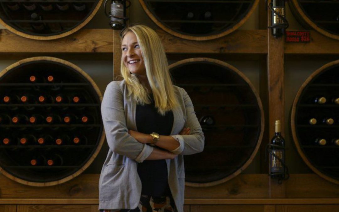 woman poses in front of wine cases